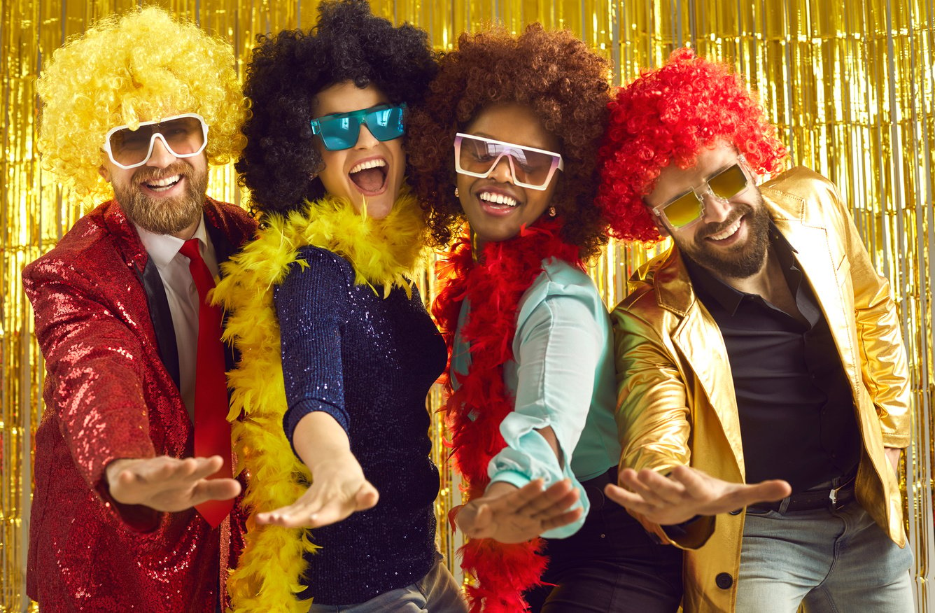 Happy Young People in Feather Boas and Curly Wigs Dancing and Having Fun at the Club